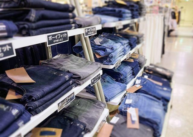 いくつものジーンズが並べられた商品棚の写真
