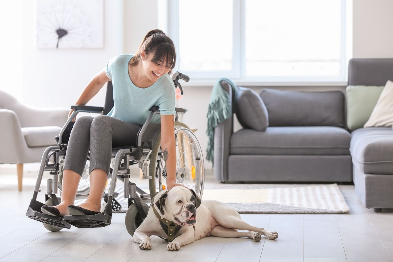 Woman on a wheelchair with a dog besides her on the floor