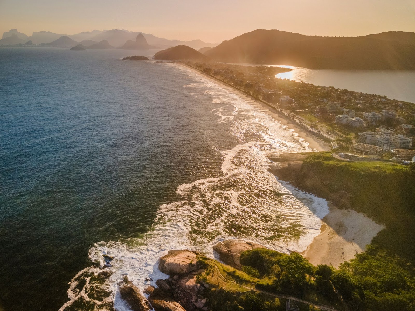 Vista aérea do oceano chegando à costa de Niterói.