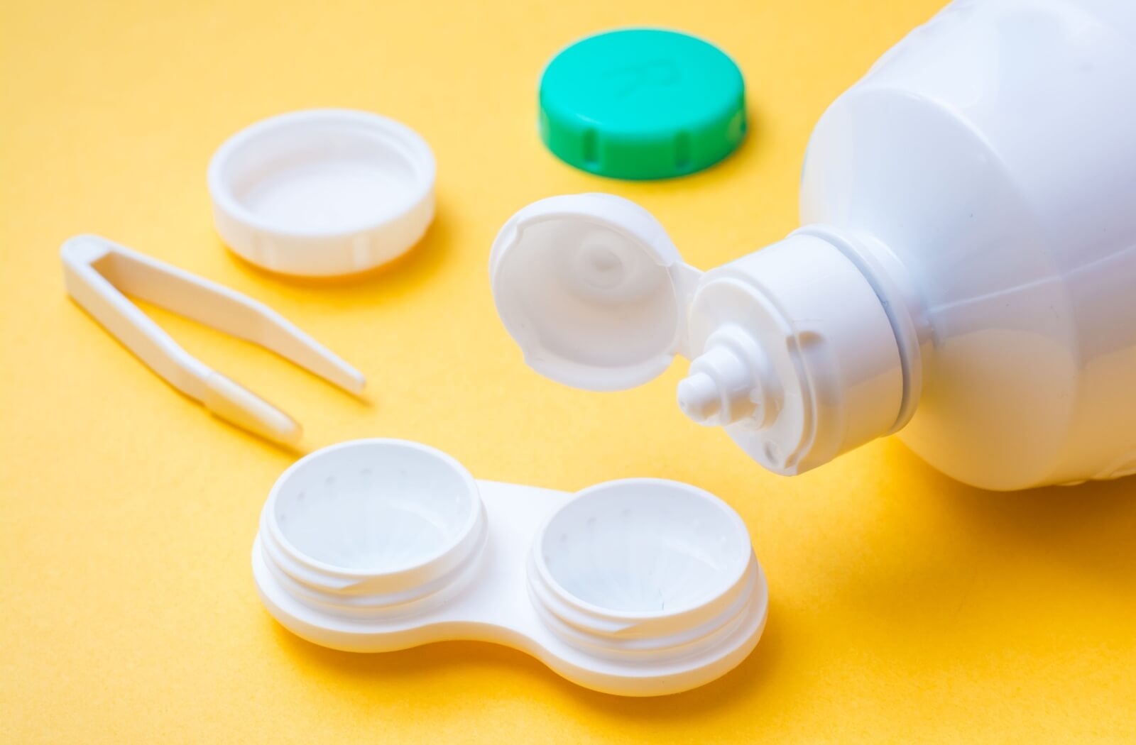 Contact lens cleaning solution being poured into a plastic container for contact lenses.