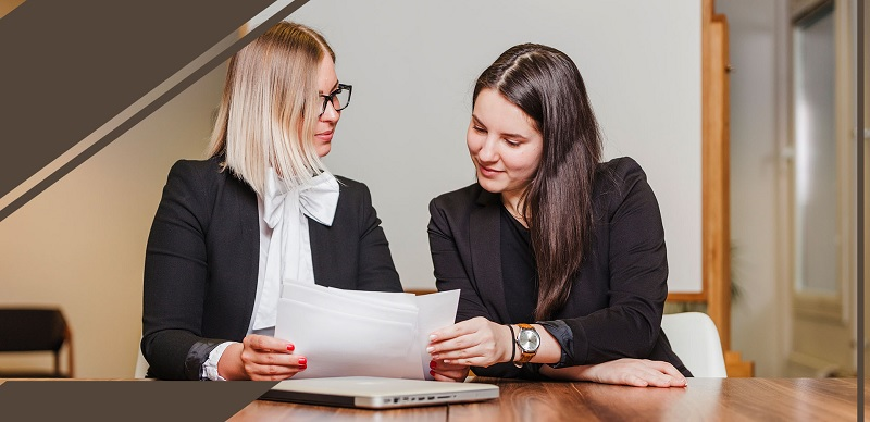 Two women looking at papers

Description automatically generated