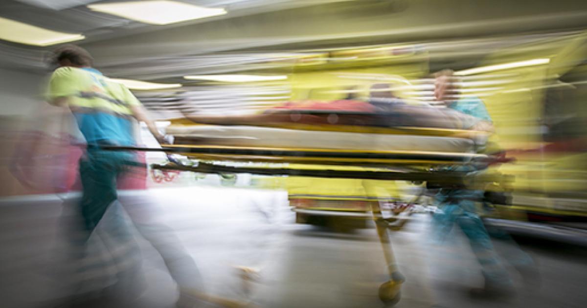 A group of people pushing a stretcher

Description automatically generated