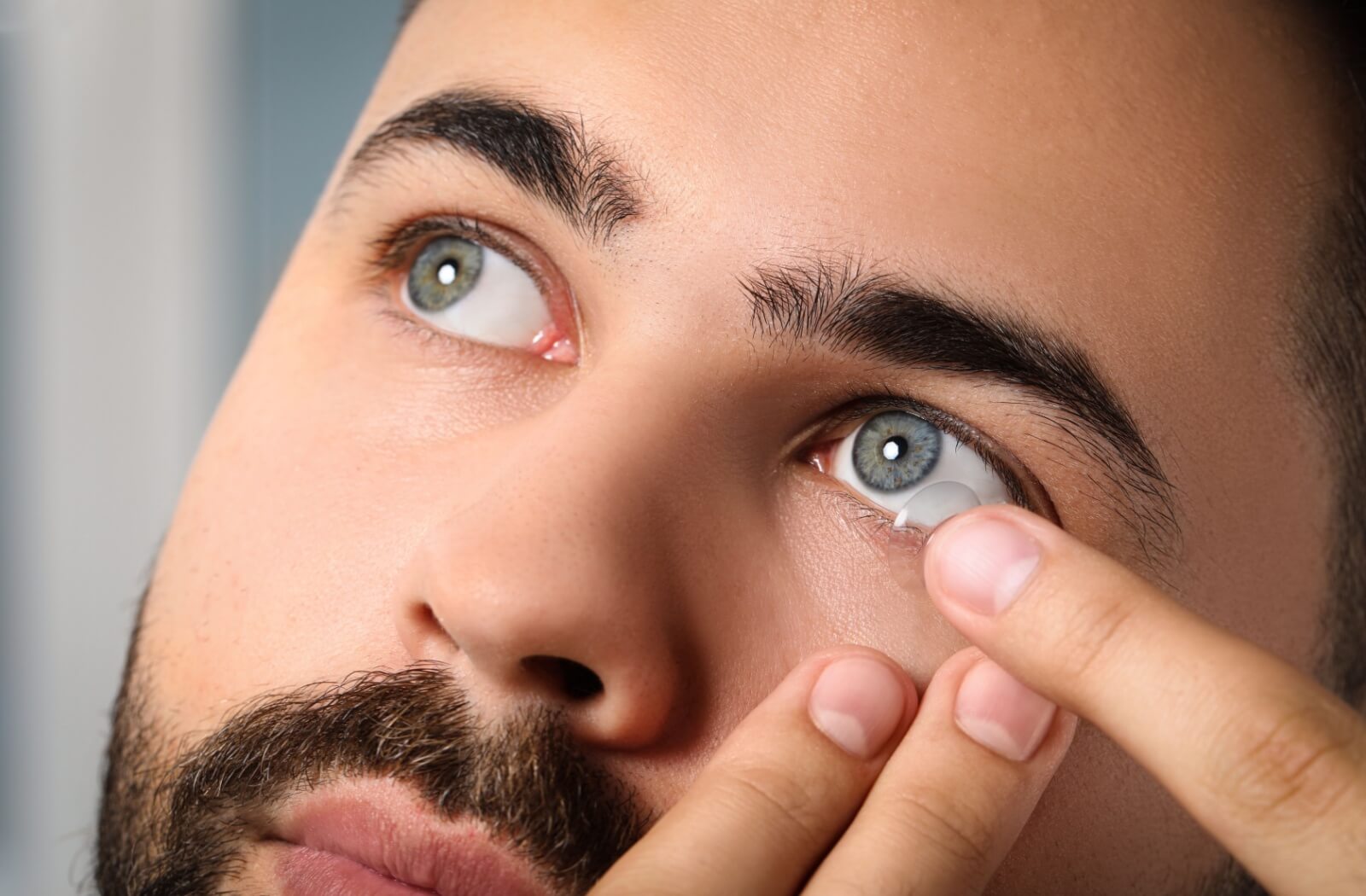 A close-up of a man putting on a myopia Misight contact lens on his left eye.