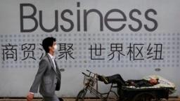 资料照 - 一位中国拉三轮工人在他的三轮车上休息。背景是一招商广告。