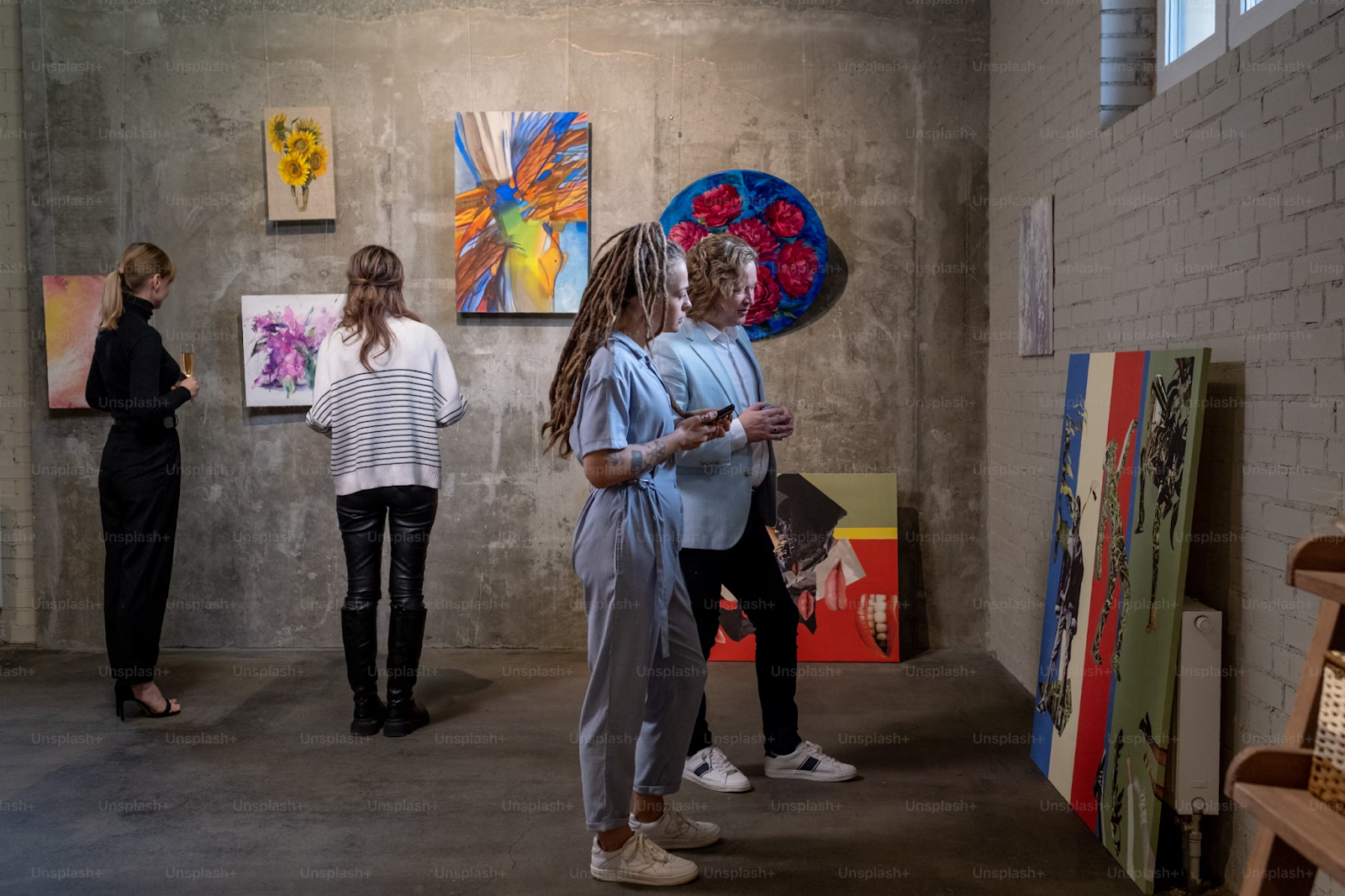 Female visitors of contemporary art gallery looking at different pieces