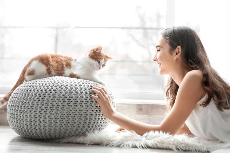 joven dueña de un gato jugando con su mascota en casa