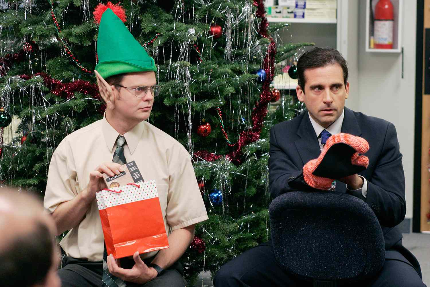 Dwight wearing elf ears with Michael sitting to his right during a game of yankee swap where he receives Phyllis's present (the oven mitt). One of the best holiday tv episodes.