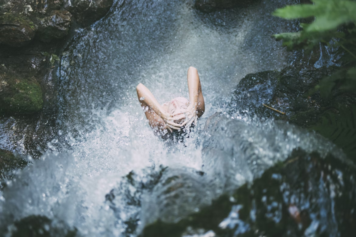 a woman using a waterfall to bathe herself