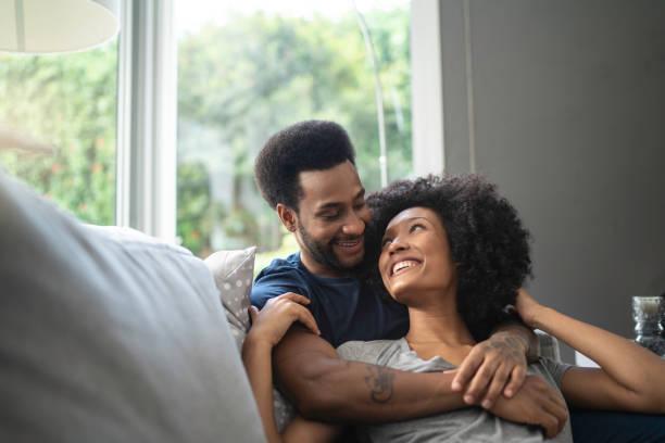 african couple lying down and having romantic moment on couch - black man love stock pictures, royalty-free photos & images
