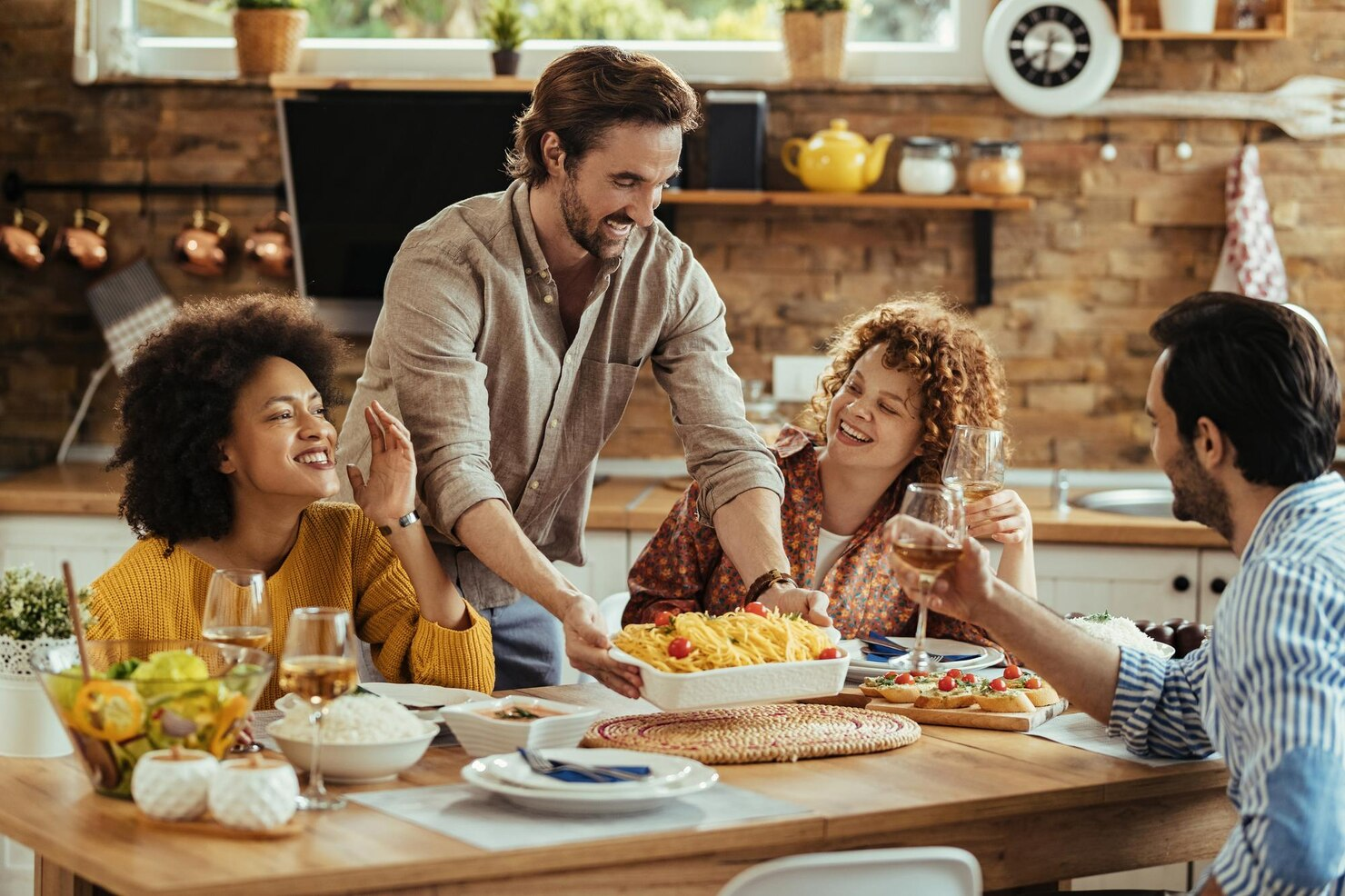 A man serving food for his friends at Friendsgiving.