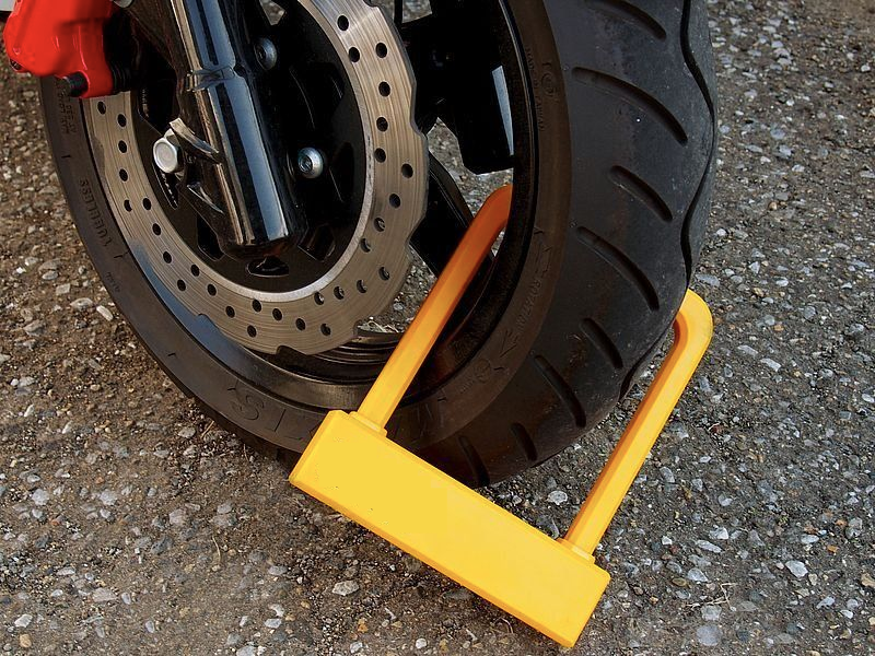 An image showing a bright yellow u-lock through the wheel of a motorcycle.