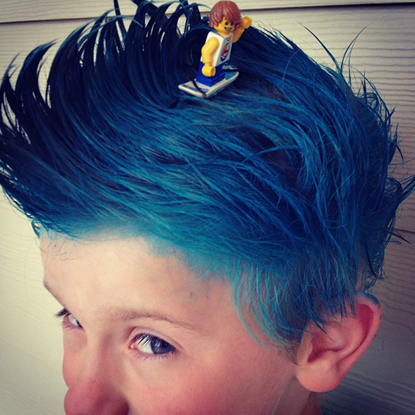 Picture of a boy wearing a hairstyle that resembles  the ocean wave with a surfer toy on it