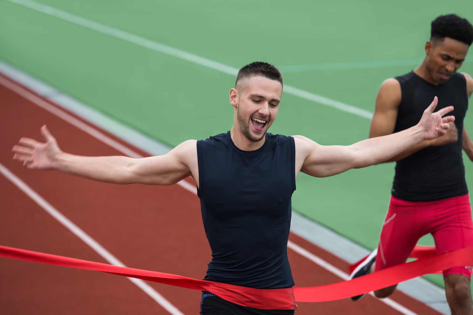 A young runner laughing as he crosses the finish line.