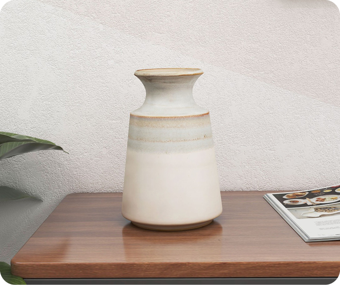 Our Nahla Ceramic Table Vase shown on a wooden surface against a textured white wall.