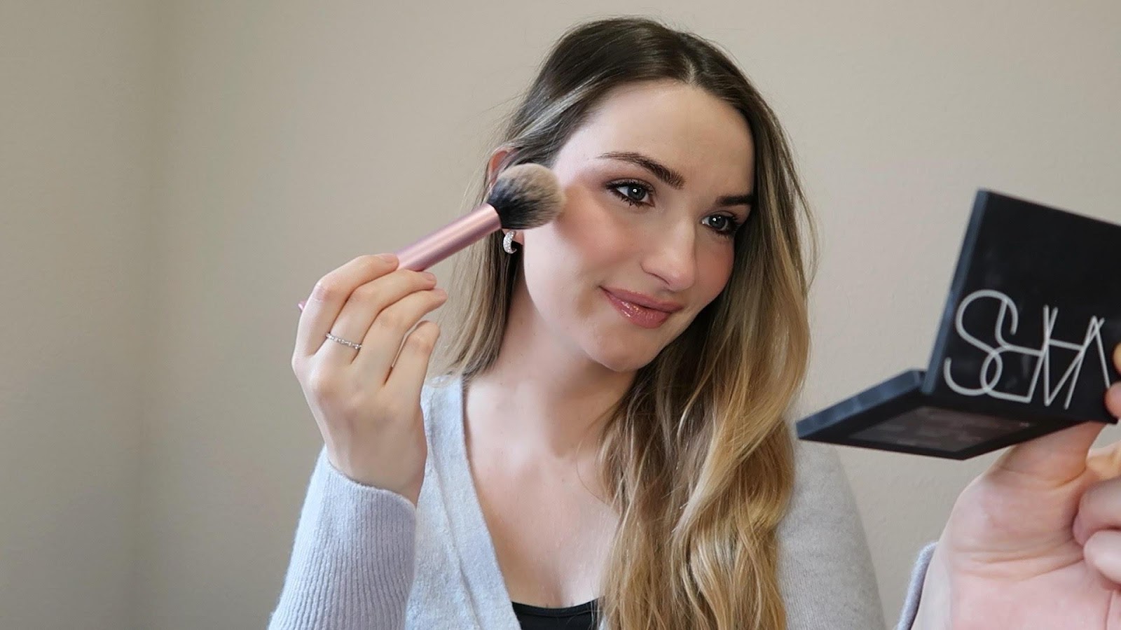 A person applying makeup with a brush

Description automatically generated