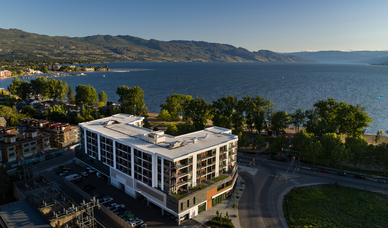 The Shore Kelowna from above, with Okanagan Lake, Gyro beach and mountains in the background