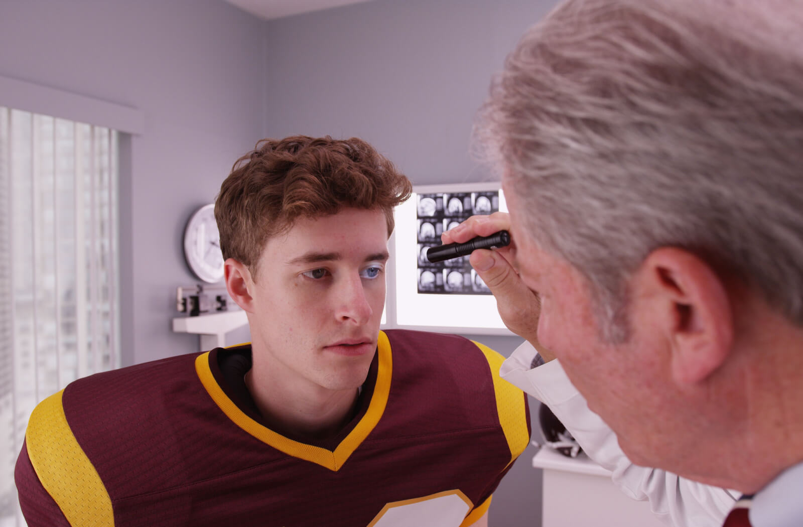 A young athlete being checked by an optometrist to see if he is concussed.