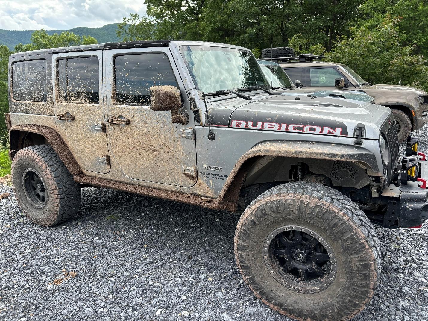 A dirty jeep parked on gravel

Description automatically generated