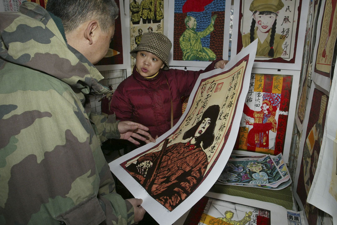 2002年11月10日，北京的潘家園市場的一位現代藝術品經銷商，向顧客展示了一幅共產黨偶像雷鋒的畫作。