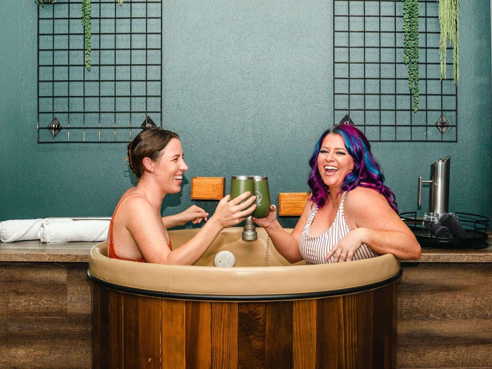 two girls smiling and hold tumblers in beer bath at Oakwell Beer Spa