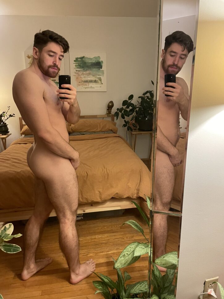 Hole Next Door posing naked in front of the mirror taking an iphone mirror selfie whiel covering his crotch and showing off his muscled bubble butt