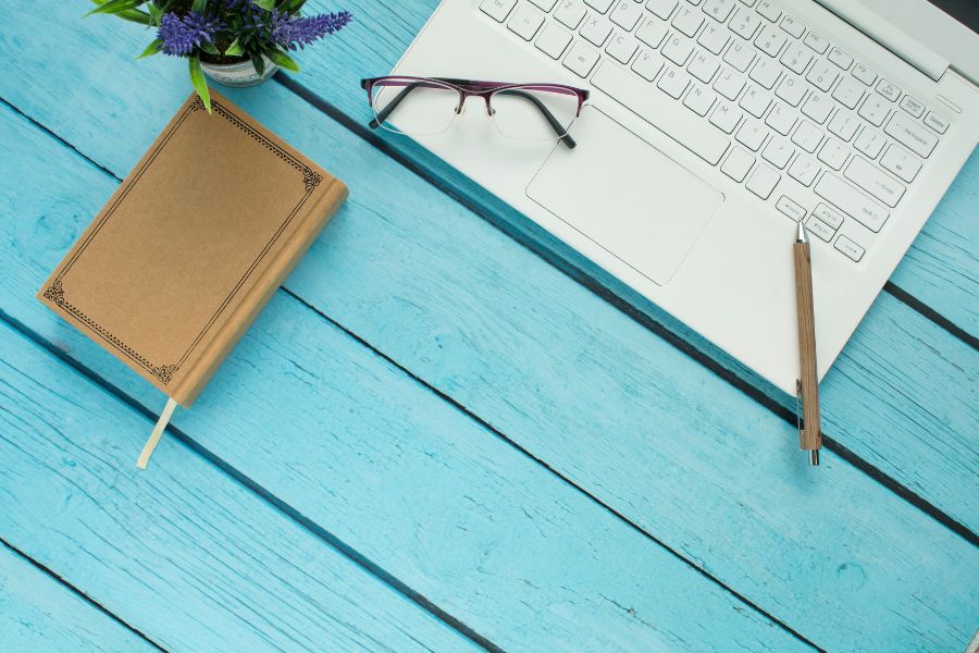 A computer and glasses on a blue table