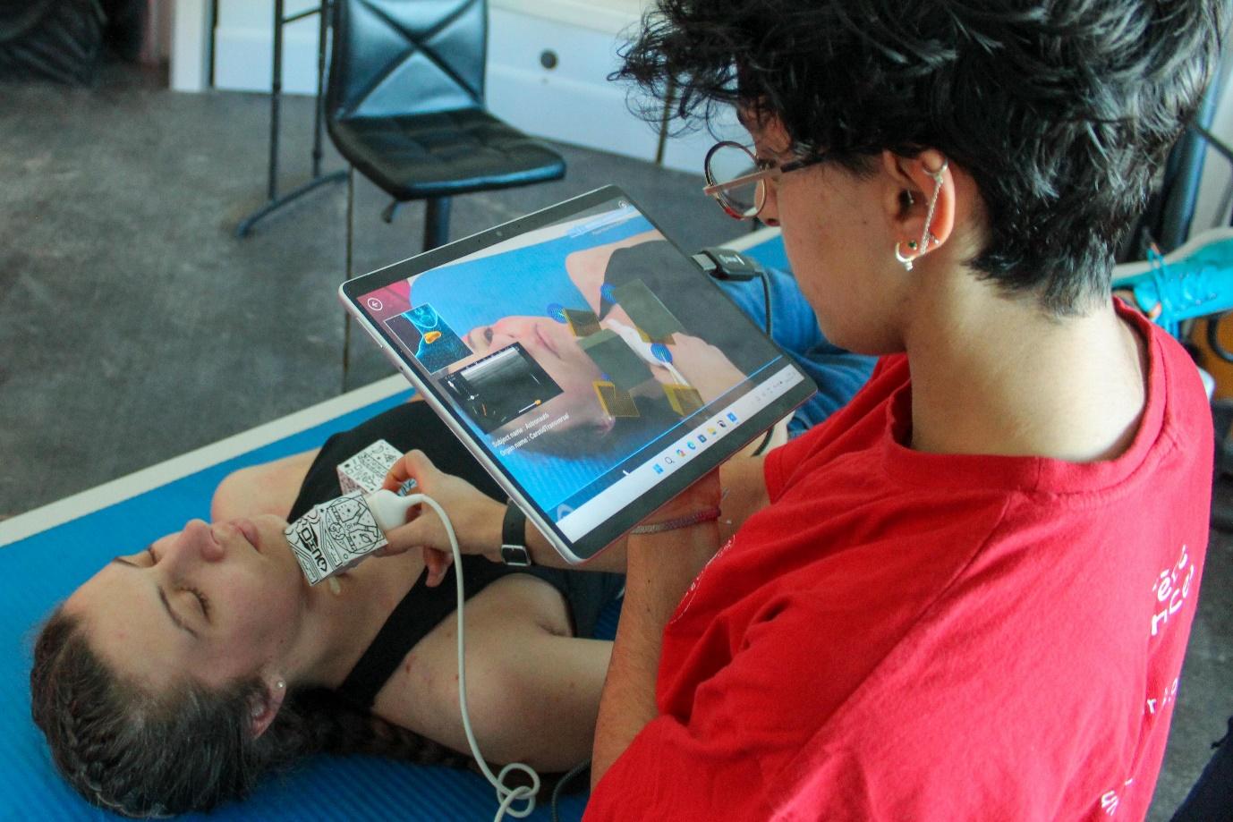 A person lying on a mat looking at a tablet Description automatically generated