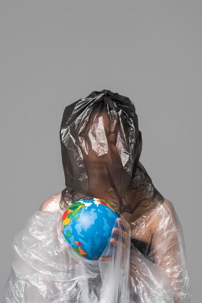 Free photo woman holding an earth globe while being covered in plastic