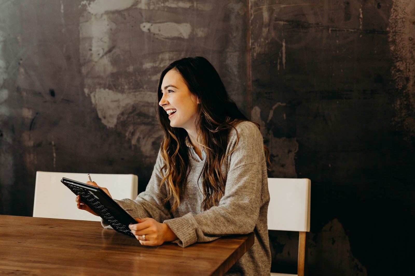 A woman engrossed in her tablet while sitting at a table, possibly working or enjoying some leisure time.