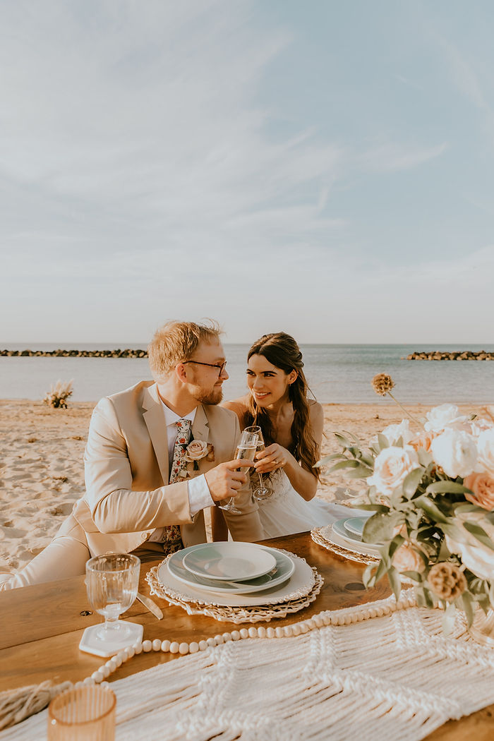 Couples poses with champagne for a luxury picnic beach elopement in Virginia Beach