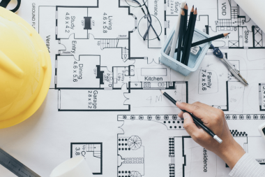 how to navigate hidden remodeling costs with design build contractors designer drawing blueprint custom built michigan