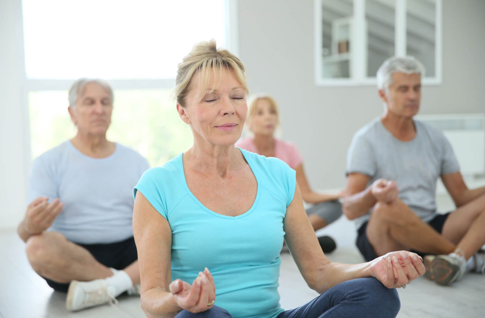 A group of older adults meditating as a part of their yoga practice.
