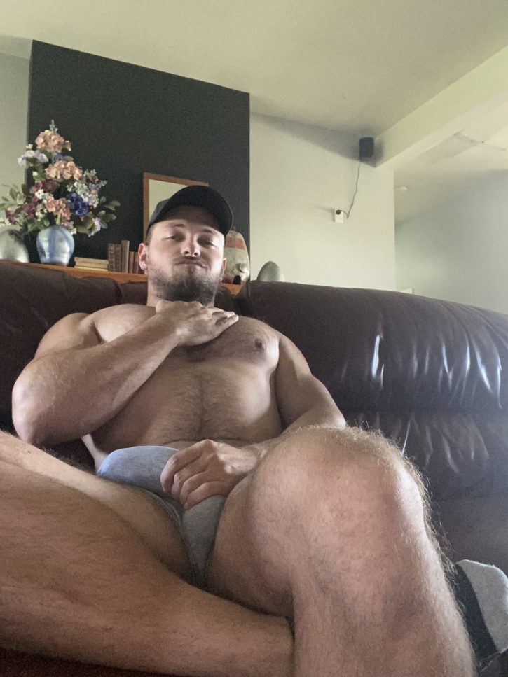 Max Small stroking his chest on the couch shirtless holding his half erect penis through the fabric of his white underwear