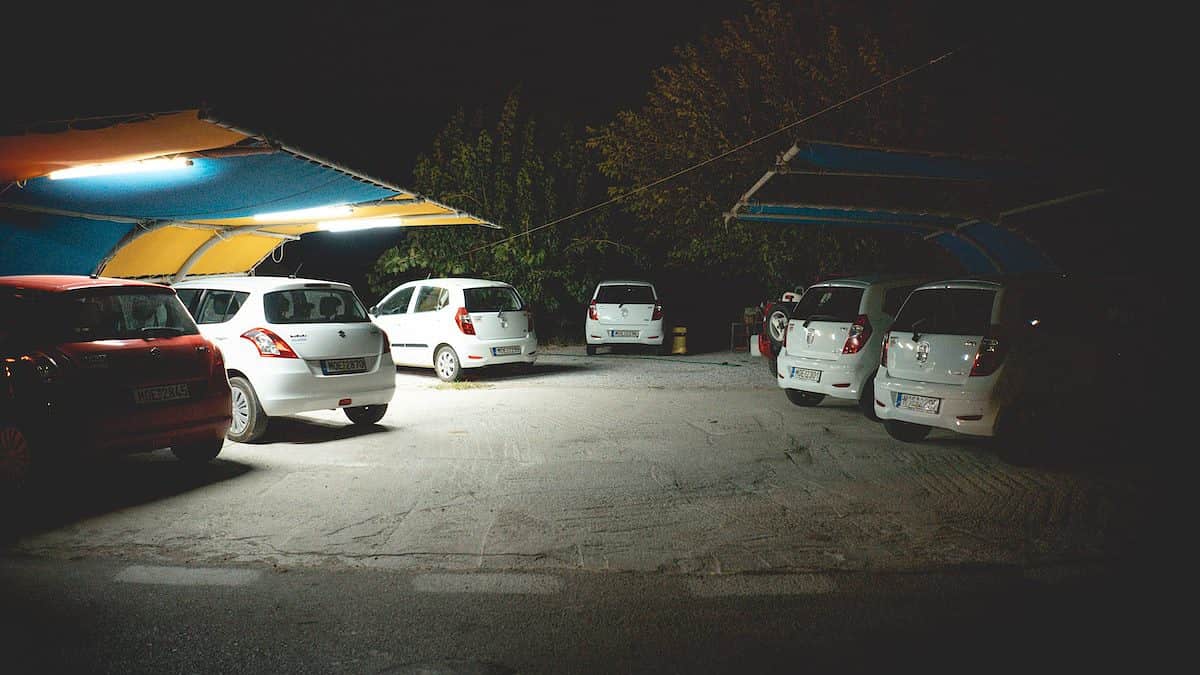 several vehicles parked beside sheds