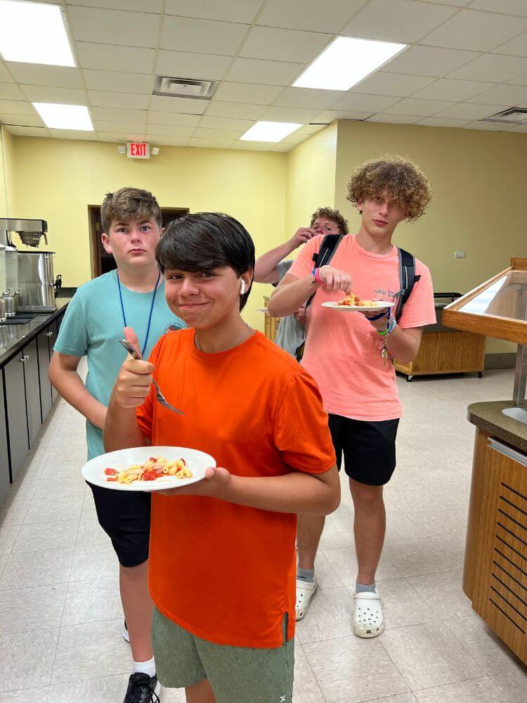 Boys at an overnight sports camp enjoying their pasta in the campus cafeteria