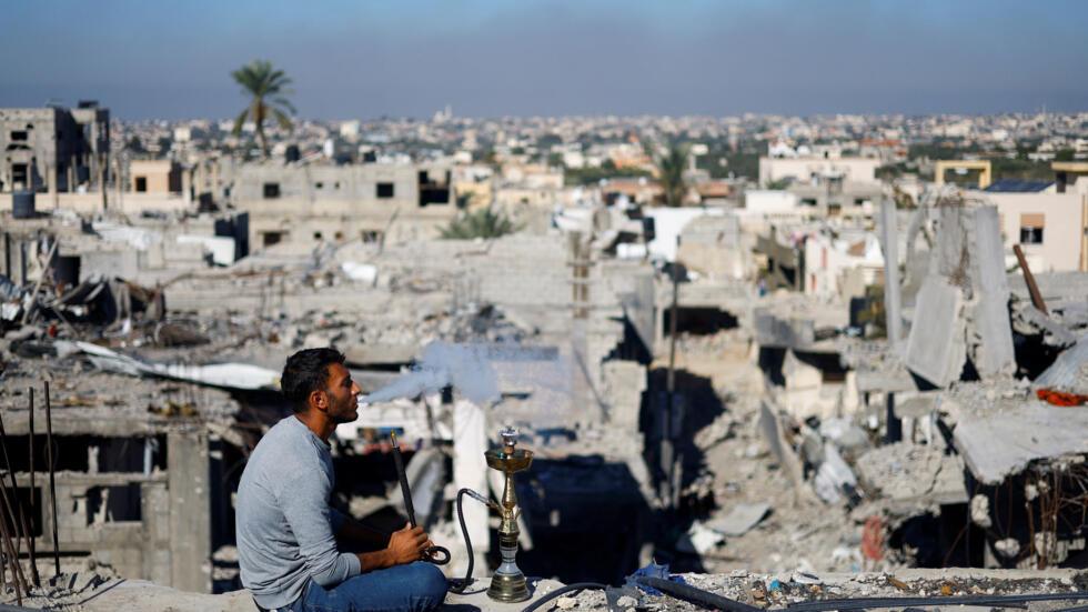 Un Palestinien fume une chicha devant un paysage de destruction,  Khan Youns, le 29 novembre 2023.