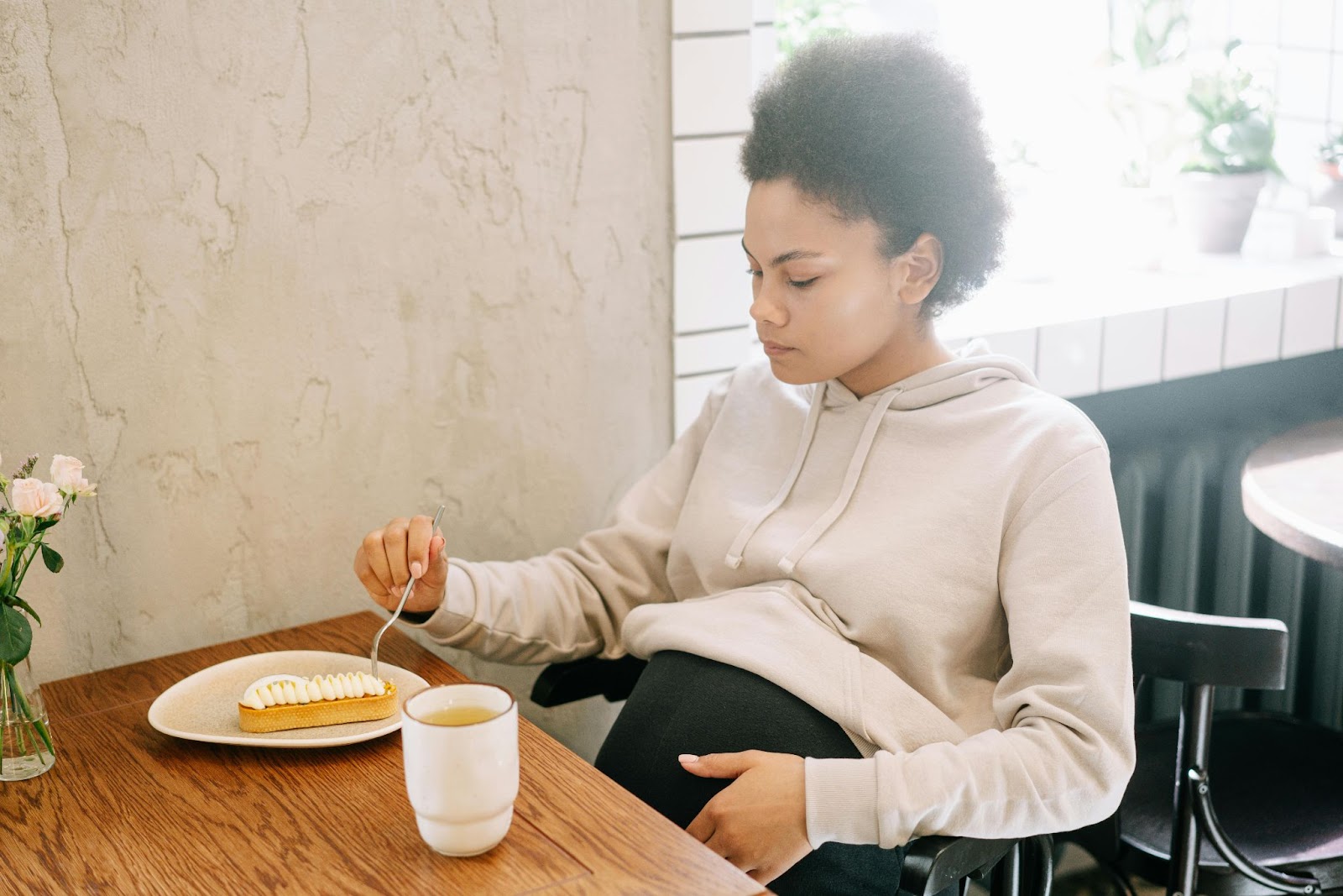 a pregnant woman eating a pie and a cup of tea