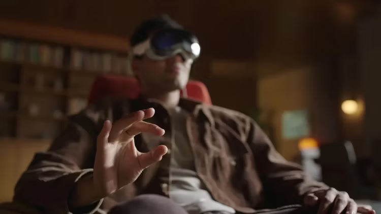 A person wearing Apple Vision Pro, making gestures with his hand to send commands.