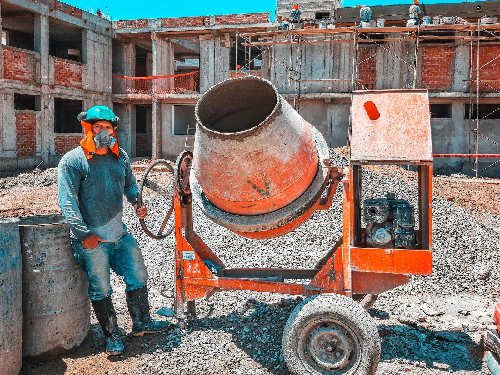 Construction worker operates a concrete mixer, a key piece of heavy construction machinery