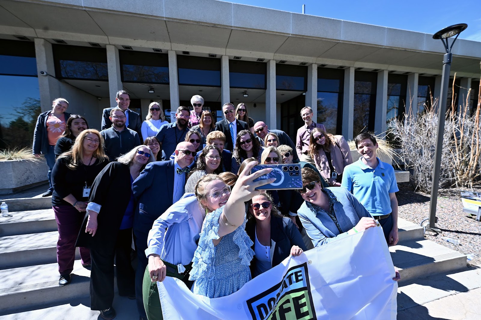 Sixteen-year-old Lella Young takes a selfie with about 20 people Thursday, April 4, 2024, after a flag-raising ceremony at DMV headquarters in Lakewood.