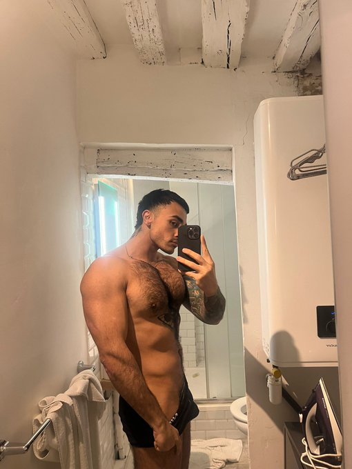Nick_at_Night taking a mirror selfie in the bathroom pull down his black underwear to show off his hairy bush