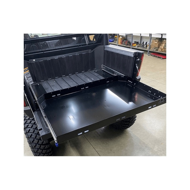 The Polaris Xpedition Bed Drawer by AJK Offroad, shown installed on a Polaris UTV that's parked in a garage. 