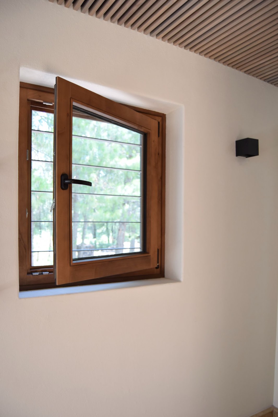 pared blanca con una ventana abatible de madera ligeramente abierta