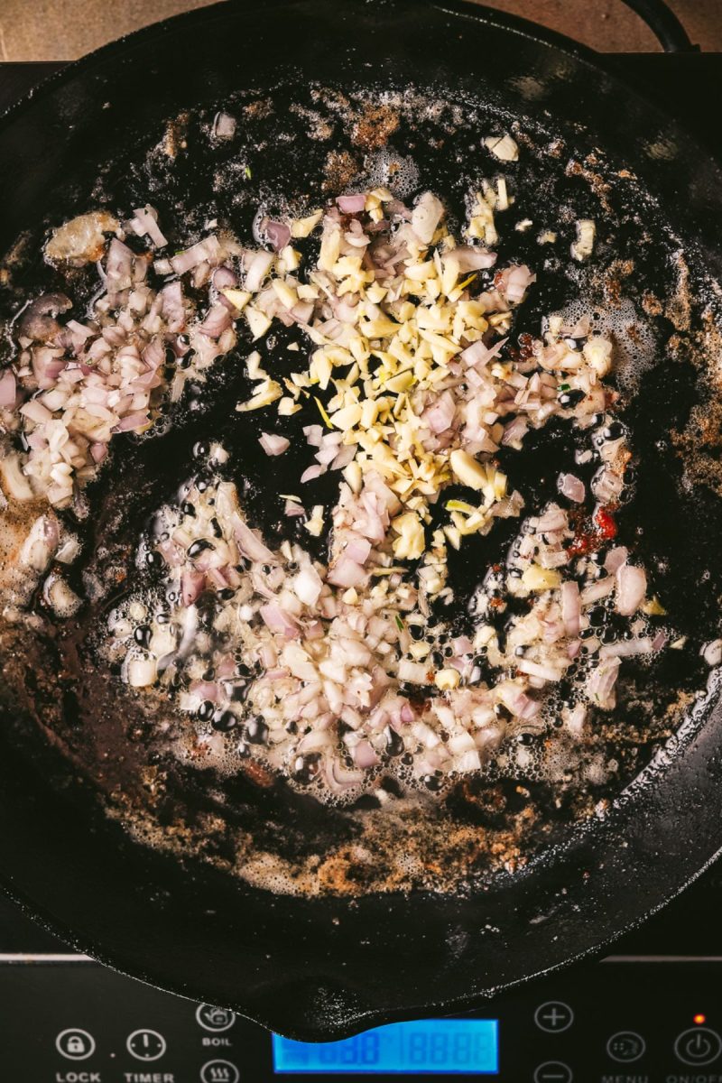 A sizzling frying pan with onions and garlic, cooking up a flavorful champagne chicken dish.