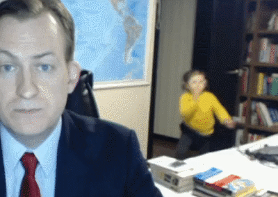 A man on a video call and a child dansing behind him