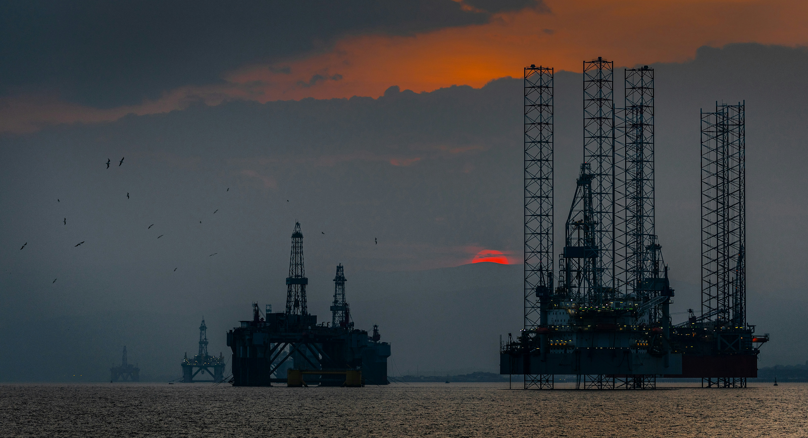 Oil rigs on the ocean at sunset