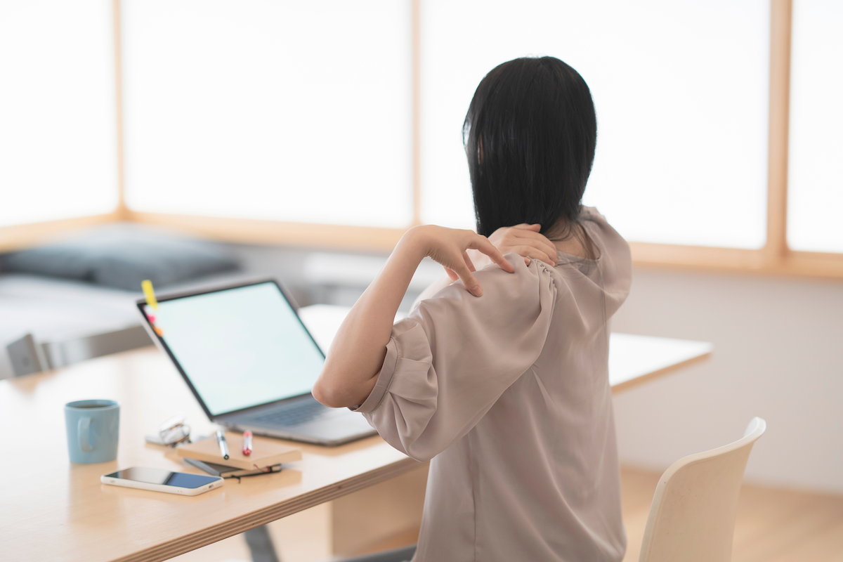 パソコンや事務作業などのデスクワークによる、猫背などの影響からくる肩こりや肩の痛みに悩む女性の画像