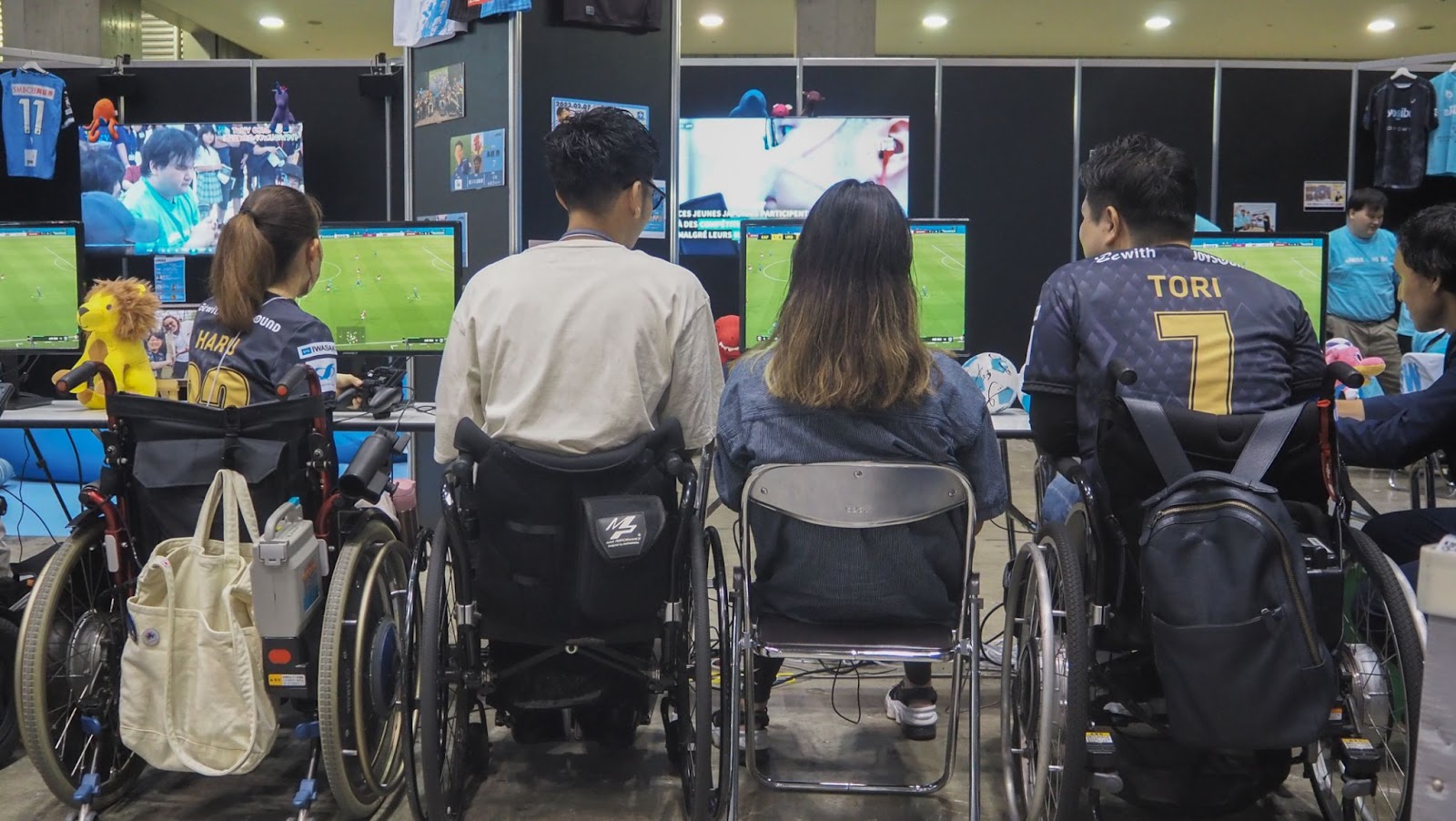 ePARAユナイテッドはる選手と鳥越選手が車いすユーザーの来場者と一緒にサッカーゲームをプレイする様子。