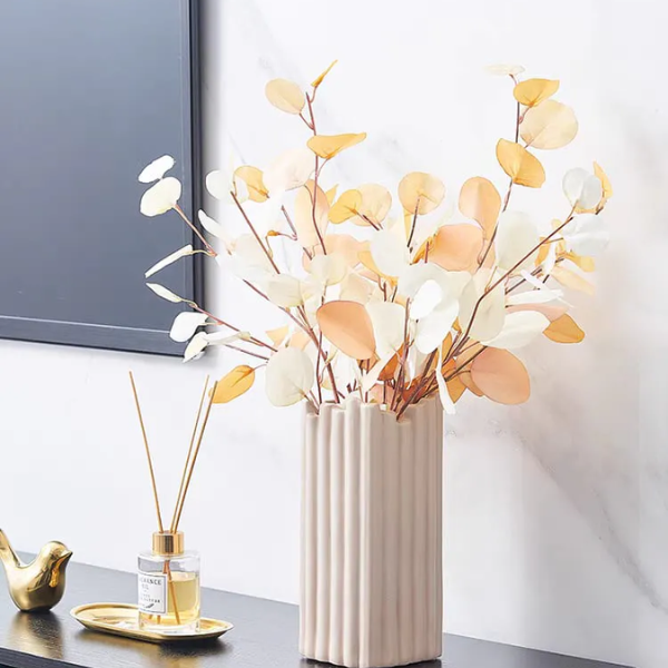 Beige ceramic vase with orange and white artificial flower arrangements