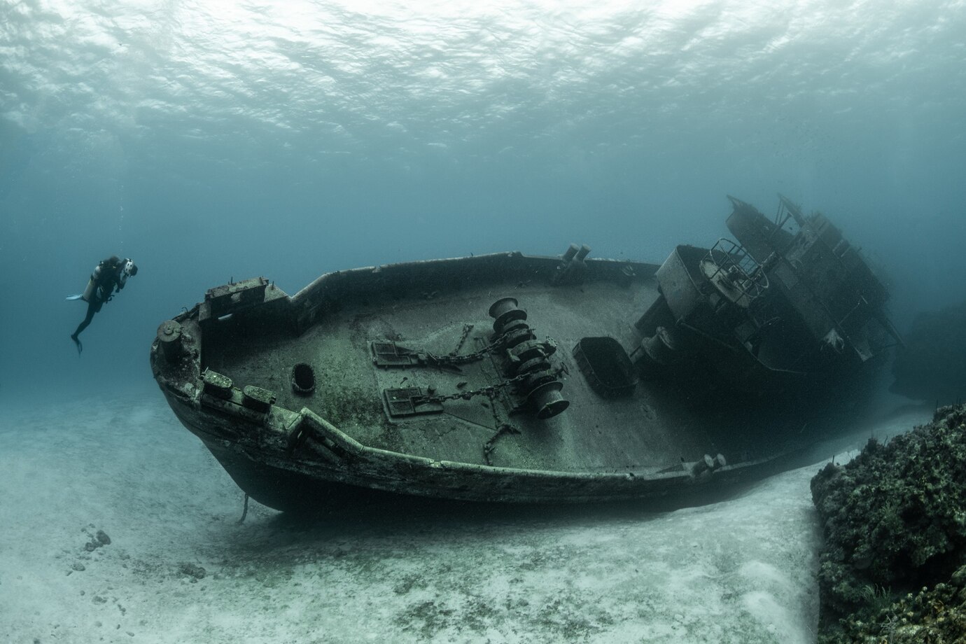 A photo of a diver looking at a shipwreck.